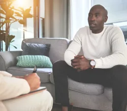 A man talking to a psychologist or therapist. A young african american guy getting help during a therapy session with a counsellor